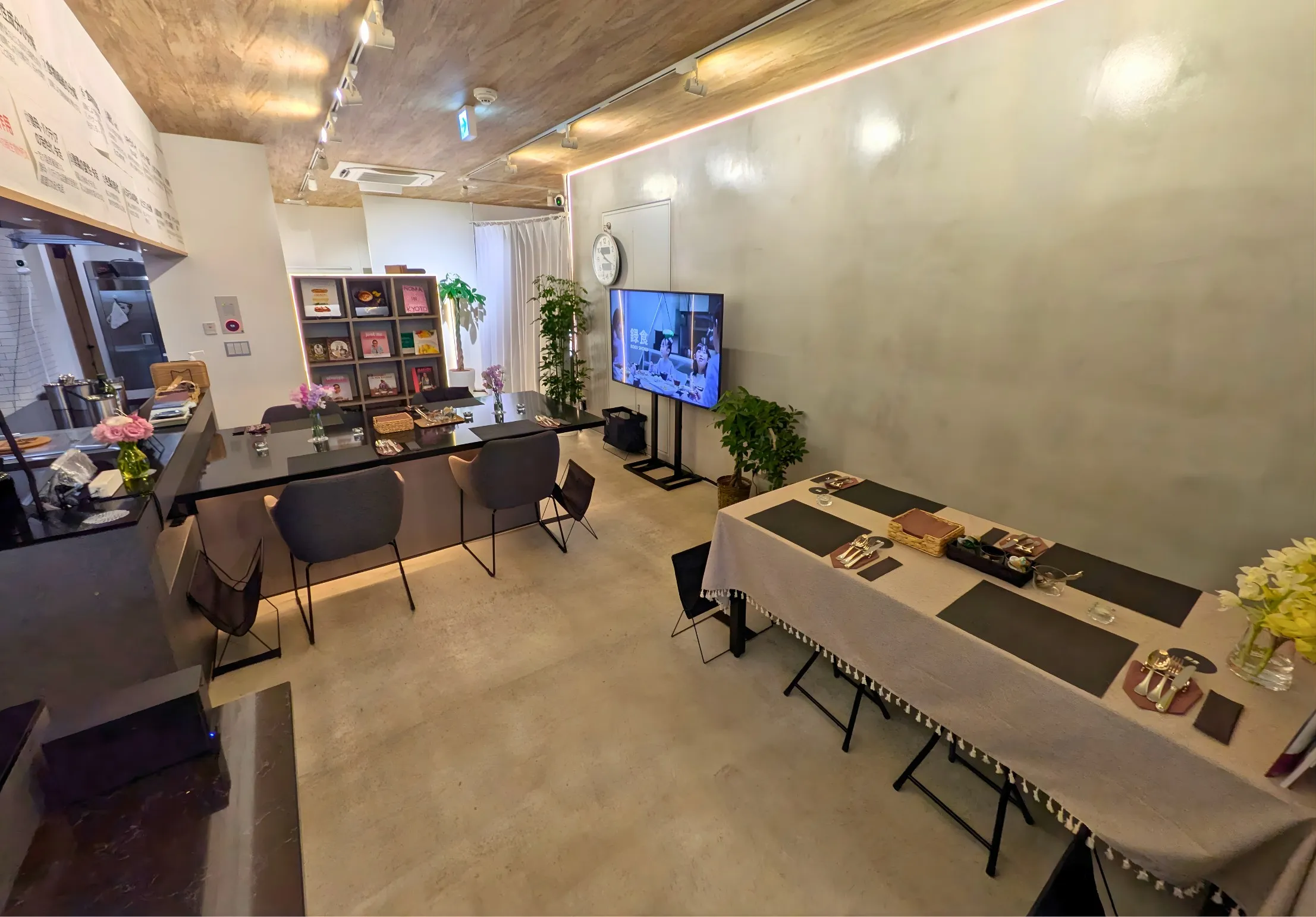 京橋キッチン by 録食の店内。カウンター席とテーブル席があり、奥のモニターに録食の映像が流れている。